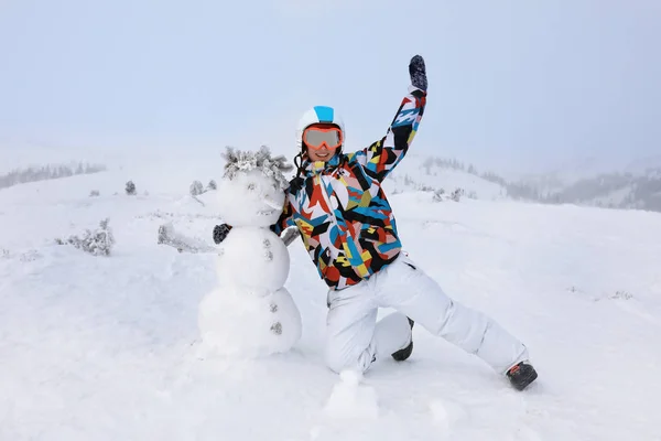 Lycklig kvinna med snögubbe på resort. Vintersemester — Stockfoto