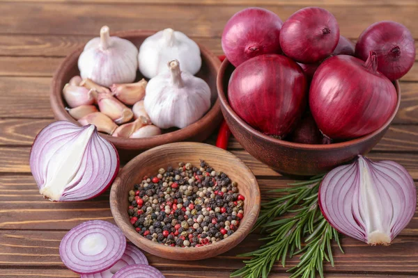Kommen met rode ui, knoflook en kruiden op tafel — Stockfoto