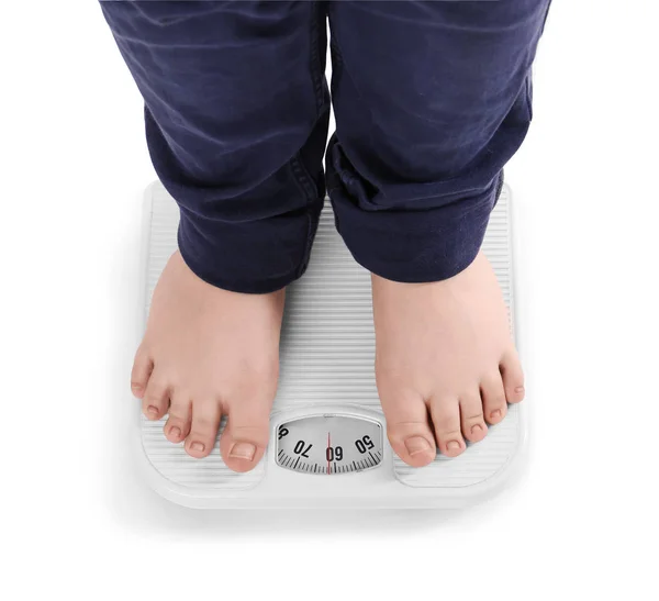 Overweight boy standing on floor scales against white background — Stock Photo, Image