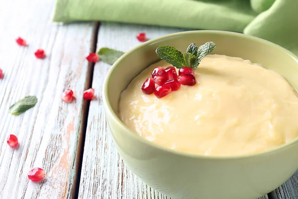 Leckerer Vanillepudding mit Granatapfelkernen in Schüssel auf dem Tisch — Stockfoto