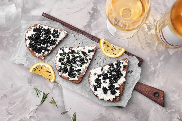 Sandwiches con delicioso caviar negro sobre tabla de madera —  Fotos de Stock