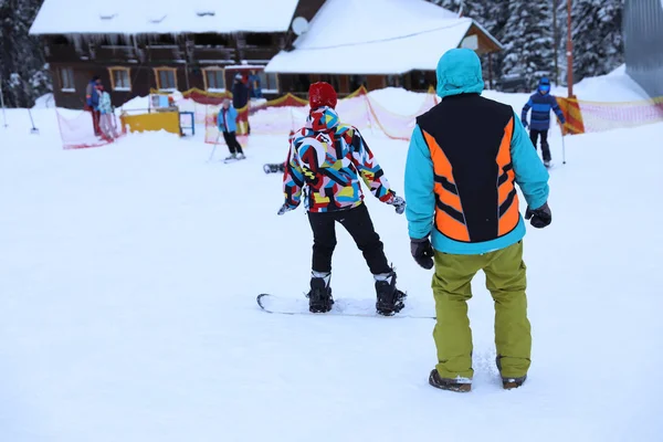Instrutor dando aulas de snowboard para a jovem mulher no resort nevado. Férias inverno — Fotografia de Stock