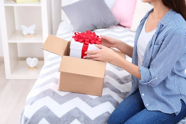 Woman taking gift box out of parcel at home — Stock Photo, Image