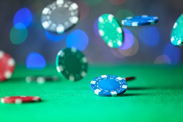 Gambling chips falling on green table in casino — Stock Photo, Image