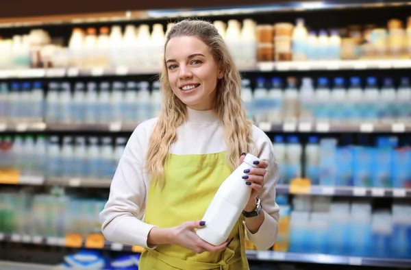 Νεαρή γυναίκα με το μπουκάλι γάλα στο κατάστημα. Ιδιοκτήτης μικρής επιχείρησης — Φωτογραφία Αρχείου