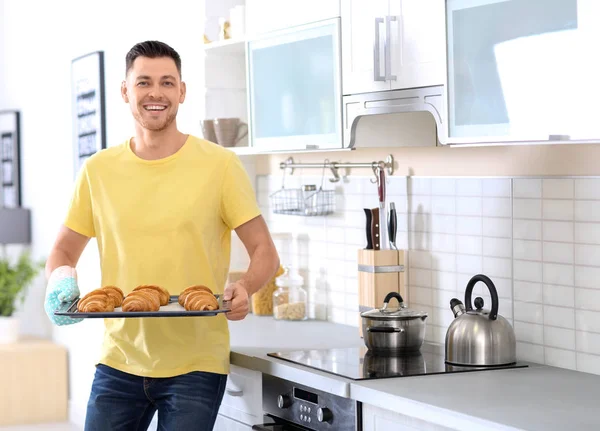 在厨房里拿着美味自制牛角面包的男人手持烤盘 — 图库照片