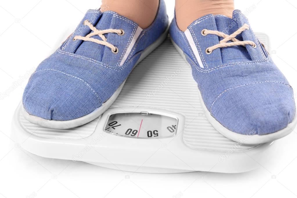 Overweight girl standing on floor scales against white background