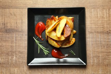 Lezzetli fırında patates dilimleri ve masada sos ile plaka