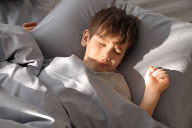 Evde yatakta uyuyan sevimli küçük çocuk