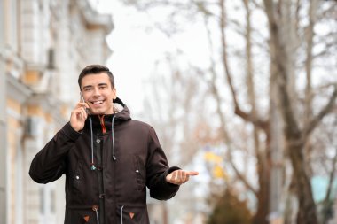 Genç adam dışarıda telefonla konuşuyor.