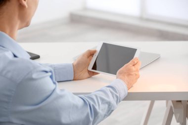 Genç adam masada kapalı tablet bilgisayar kullanarak