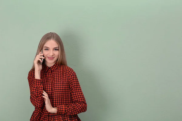 Belle jeune femme parlant sur téléphone mobile près du mur de couleur — Photo