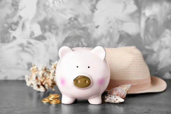 Keramische piggy bank met geld, hoed en schelpen op grijze tafel — Stockfoto