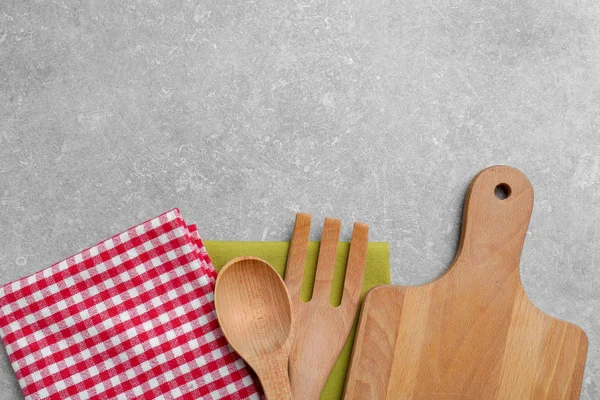Wooden cooking utensils and napkins on gray background, top view