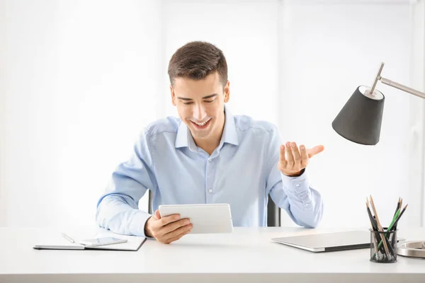 Молодой человек использует планшетный компьютер за столом в помещении — стоковое фото