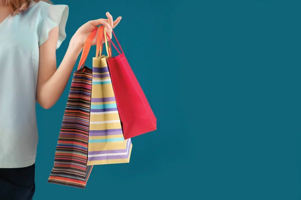 Jovem com sacos de compras em fundo de cor — Fotografia de Stock