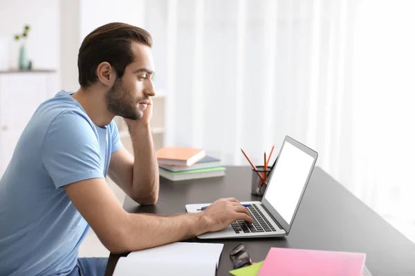 Student met laptop studeren aan tafel binnenshuis — Stockfoto