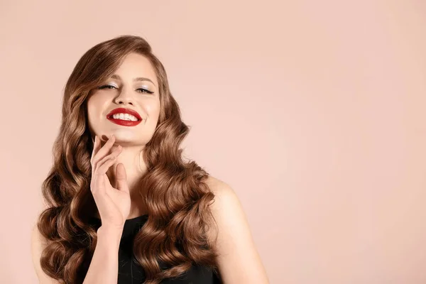 Schöne junge Frau mit langen welligen Haaren auf hellem Hintergrund — Stockfoto