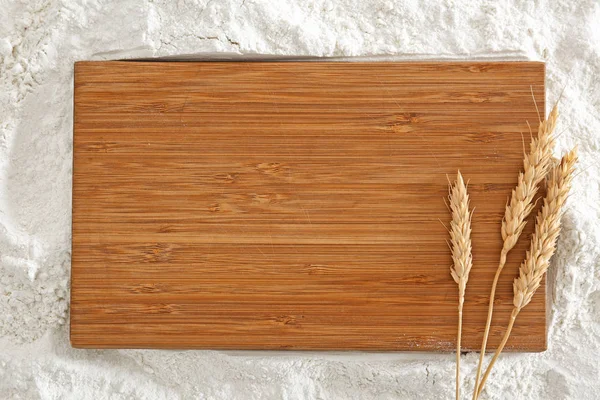 Tavola di legno con spighette sulla farina — Foto Stock