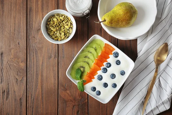 Yogurt con mirtillo, prugna di dattero e kiwi in piatto sul tavolo — Foto Stock