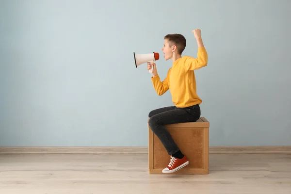 Grappig jongetje zittend op houten kubus en schreeuwen in Megafoon binnenshuis — Stockfoto