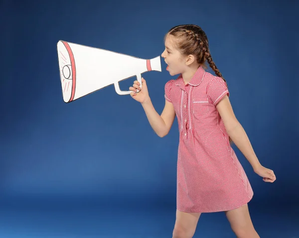 Маленька дівчинка кричить на паперовому мегафоні на кольоровому фоні — стокове фото
