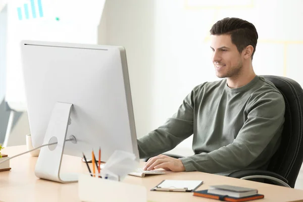 Jeune homme travaillant avec l'ordinateur à la table dans le bureau — Photo