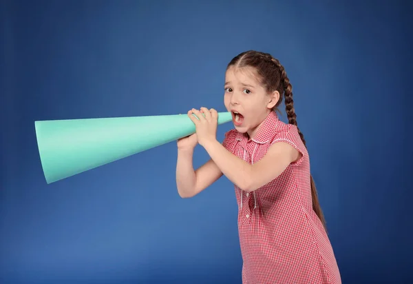 Kleines Mädchen schreit in ein Megafon aus Papier auf farbigem Hintergrund — Stockfoto