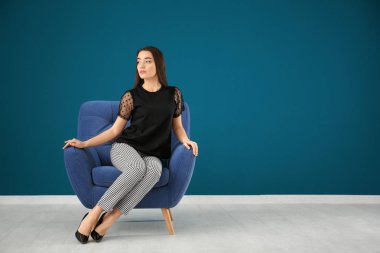 Rahat koltuk renk duvara oturan güzel genç kadın