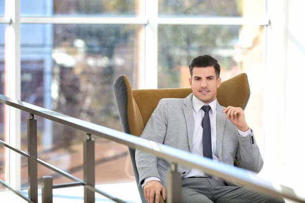 Stilig affärsman sitter i bekväm fåtölj inomhus — Stockfoto