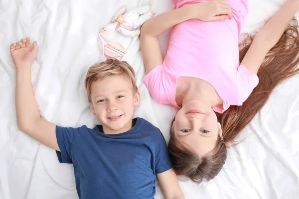 Cute little brother and sister lying on bed at home — Stock Photo, Image