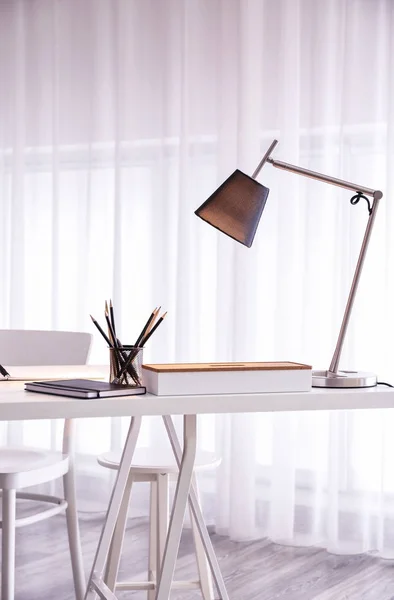 Comfortable workplace with modern lamp on table