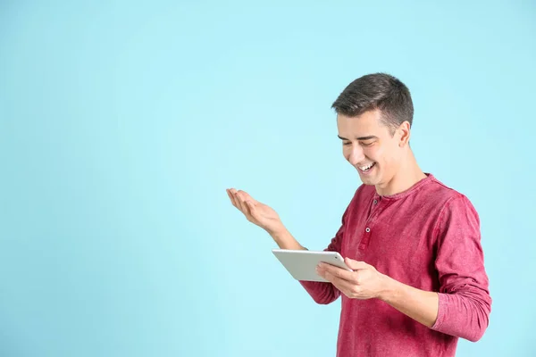 Young man using tablet computer on color background — Stock Photo, Image