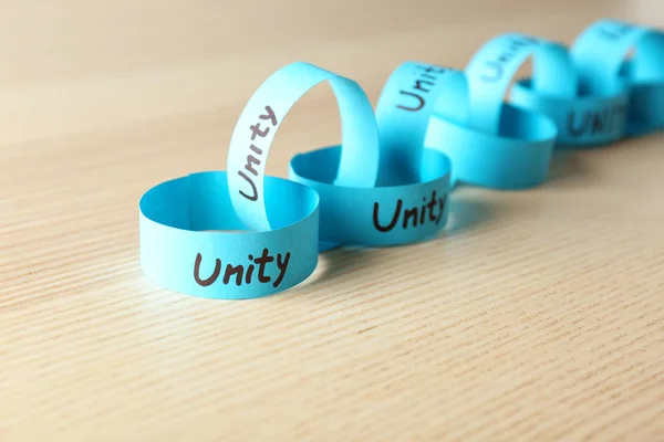 Paper chain with word UNITY on wooden background — Stock Photo, Image