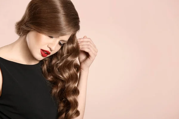 Krásná mladá žena s dlouhé vlnité vlasy na světlé pozadí — Stock fotografie