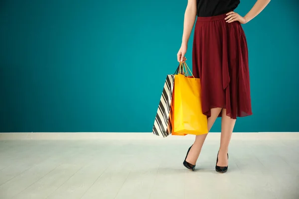 Beautiful young woman with shopping bags against color wall — Stock Photo, Image