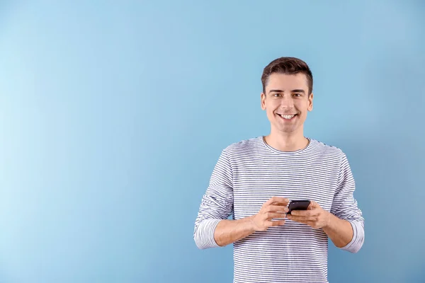 Hombre joven usando el teléfono en el fondo de color —  Fotos de Stock