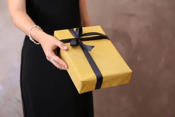 Молодая женщина держит подарочную коробку на светлом фоне — стоковое фото