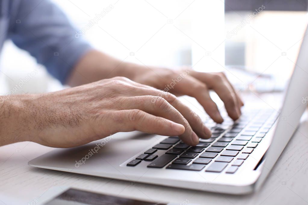 Man working with laptop at table in office