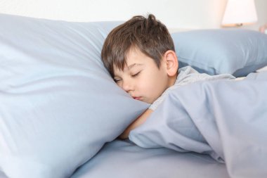 Evde yatakta uyuyan sevimli küçük çocuk