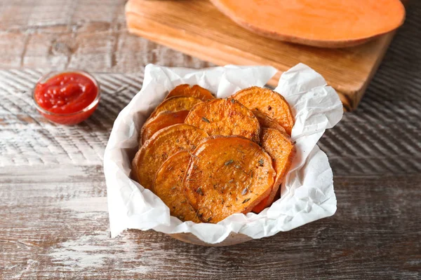 Tigela com saborosas batatas fritas na mesa de madeira — Fotografia de Stock