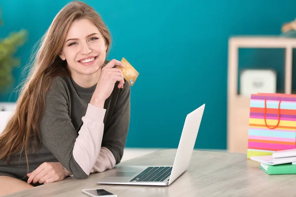 Jovem mulher compras on-line com cartão de crédito e laptop à mesa — Fotografia de Stock