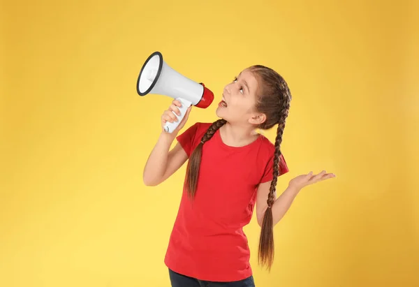 Emotionales kleines Mädchen mit Megafon auf farbigem Hintergrund — Stockfoto