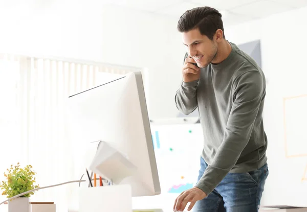 Junger Mann telefoniert während der Arbeit im Büro — Stockfoto