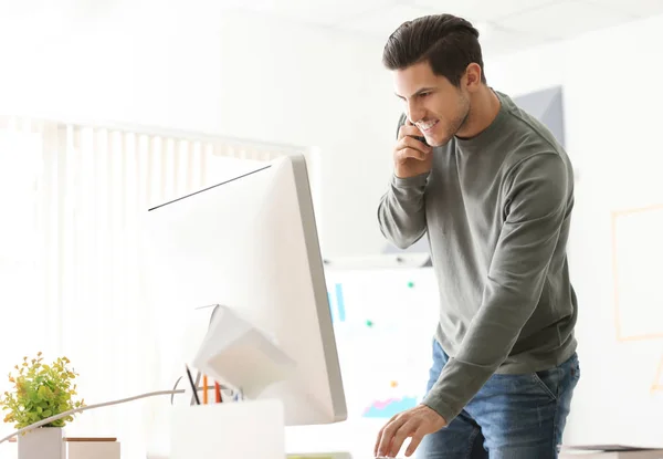 Joven hablando por teléfono móvil mientras trabaja en la oficina — Foto de Stock