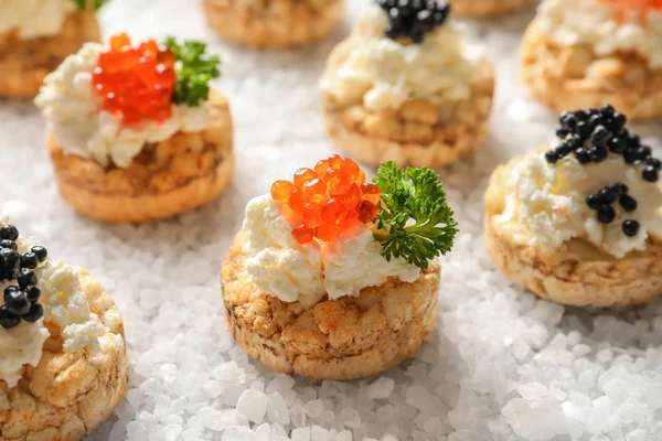 Canapés deliciosos com caviar preto e vermelho no sal marinho — Fotografia de Stock