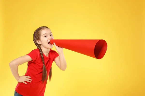 Маленькая девочка кричит в бумажный мегафон на цветном фоне — стоковое фото