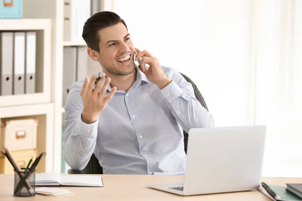 Ung man pratar i mobiltelefon medan arbetande i kontor — Stockfoto