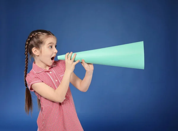 Kleines Mädchen schreit in ein Megafon aus Papier auf farbigem Hintergrund — Stockfoto