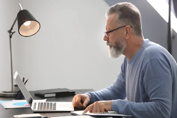 Starszy mężczyzna pracujący z laptopem przy stole w biurze — Zdjęcie stockowe